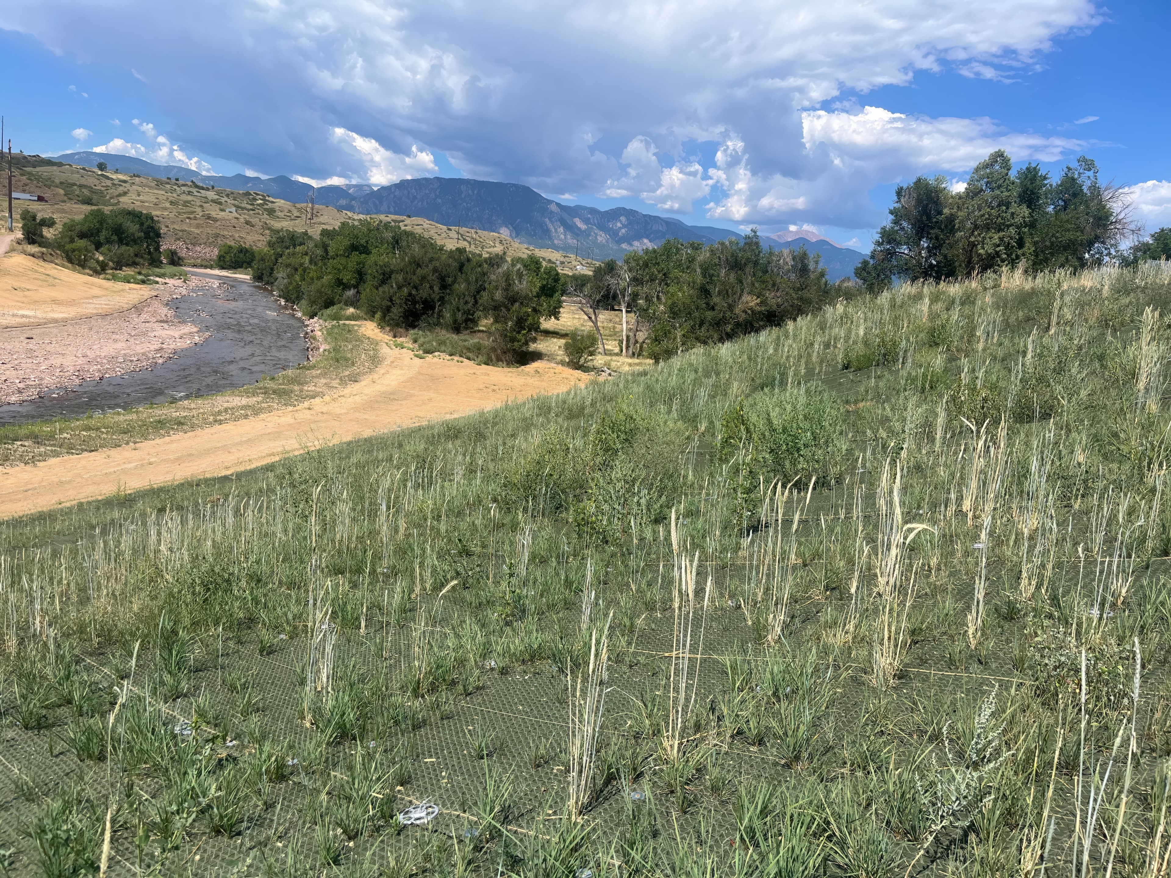 Completed slope reinforced with PROPEX® Armormax® and MIRAGRID® XT, restoring road access and reducing material transport compared to traditional rock riprap solutions.